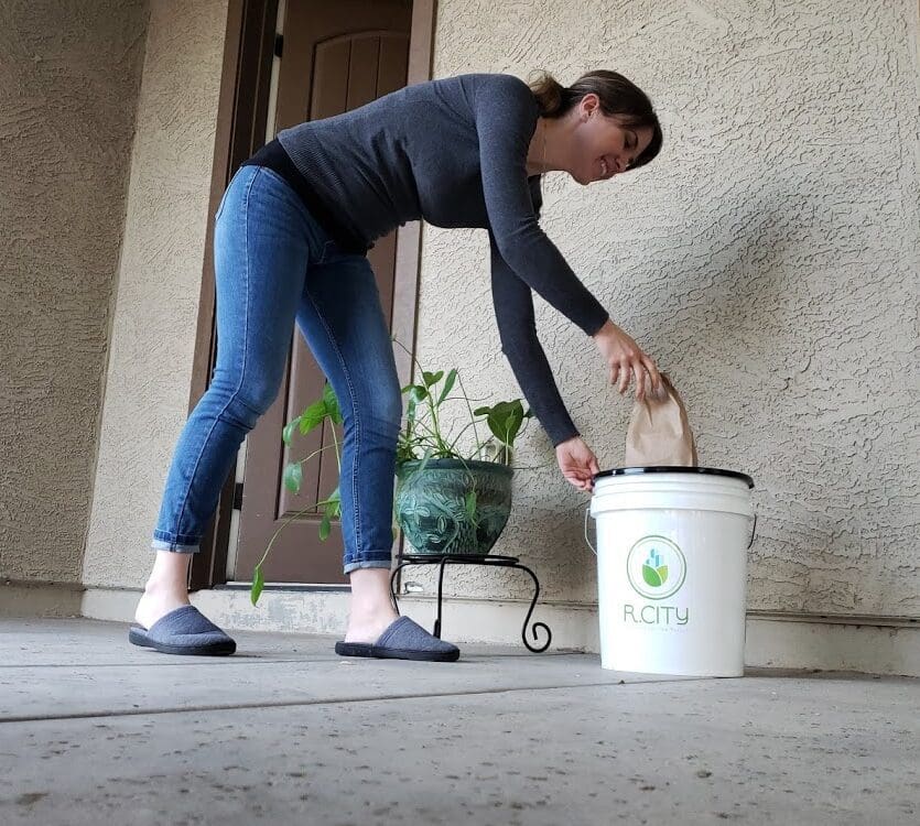 A woman is putting something in the trash can.