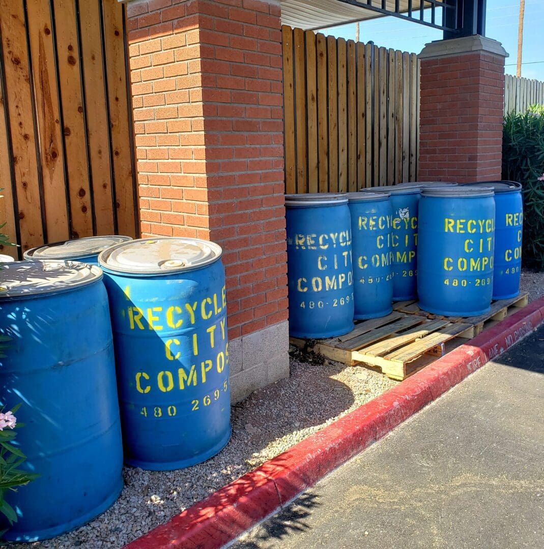 A row of blue barrels sitting next to a building.