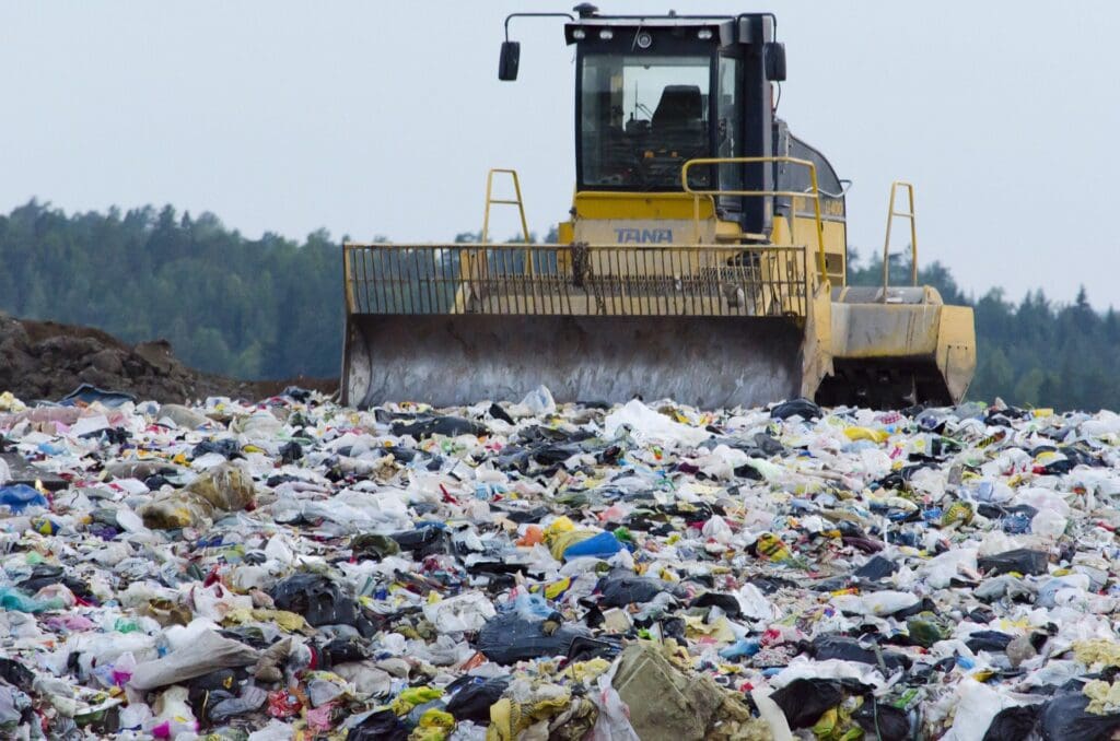 A bulldozer is moving trash in the field.