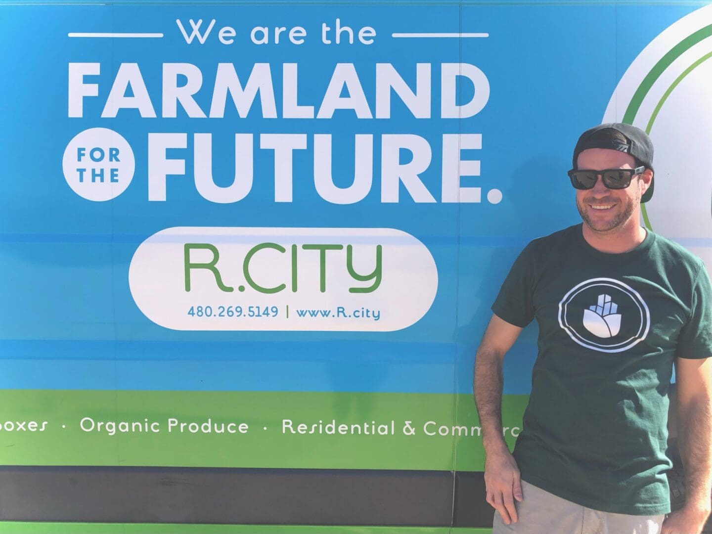 A man standing in front of a sign that says " we are the farmland for the future ".