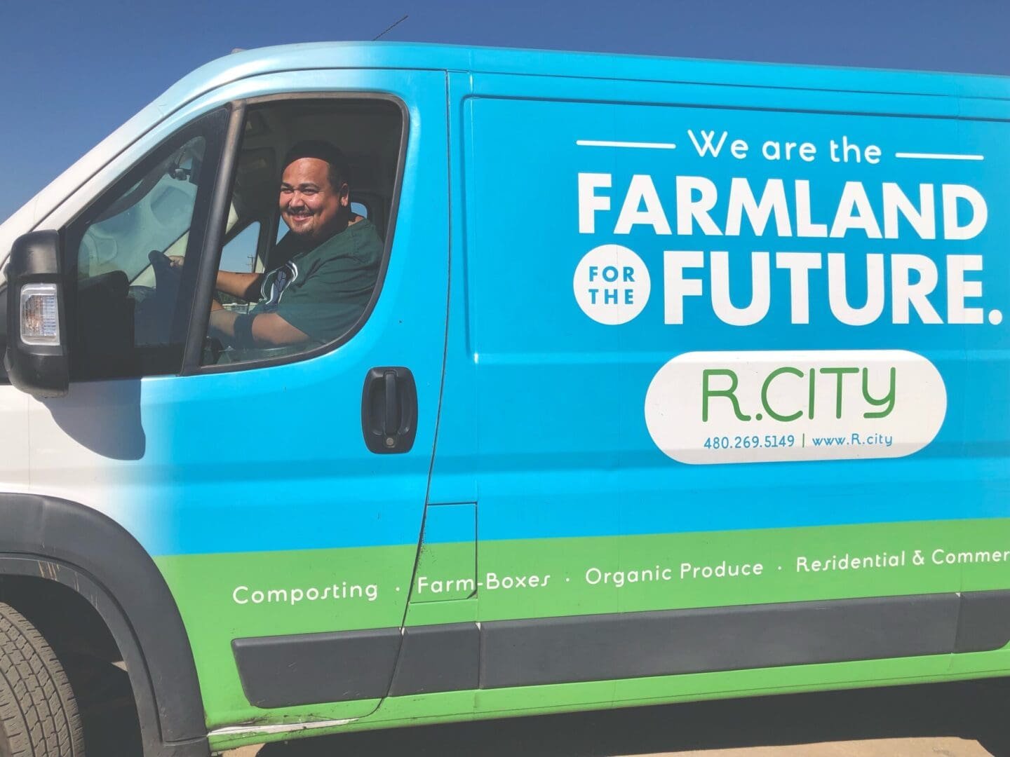 A man sitting in the drivers seat of a blue and green truck.